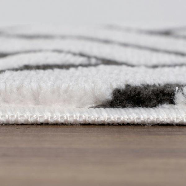 Close-up of a textured rug with white and gray pattern on a wooden floor.