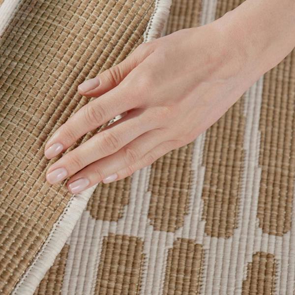 Hand touching a textured brown and beige woven fabric