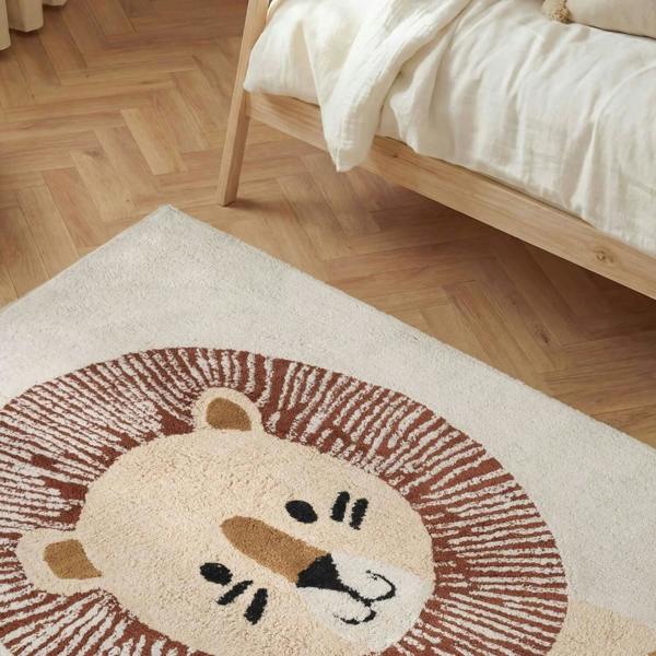 Lion-themed rug on a wooden floor with a bed in the background