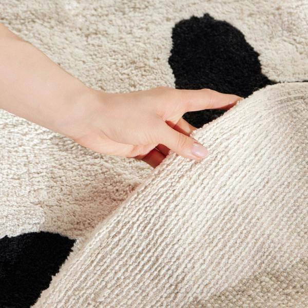 Hand touching a textured beige and black patterned fabric