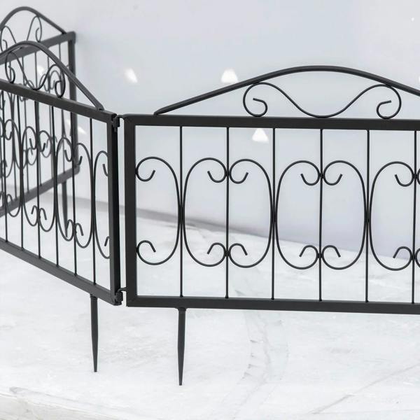 Black metal fence panels with arched scroll tops and bottom stakes, side angle