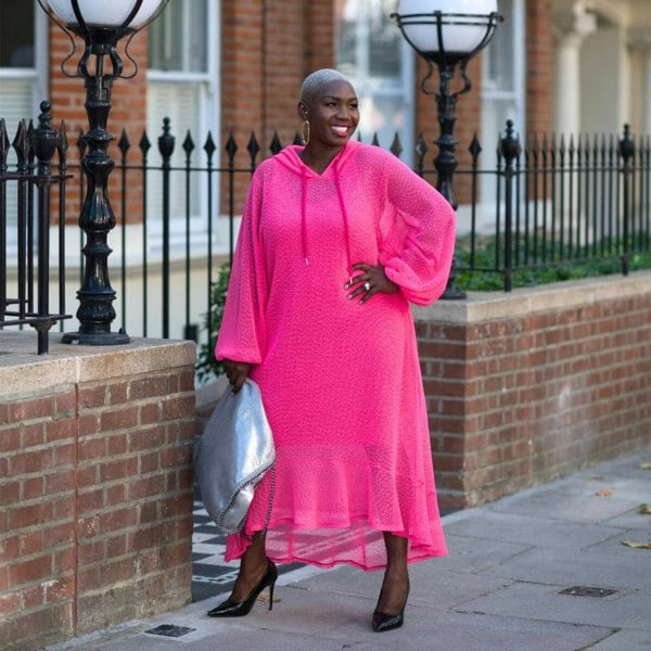 Women's Plus Size Aphrodite Hot Pink Holiday Resort Dress with hoodie and hot pink undergarment, paired with a silver handbag and black heels.