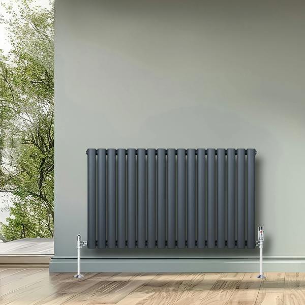 Oval single column radiator in anthracite grey, 600mm x 1020mm, featuring sleek vertical bars and chrome valves, set against a light green wall