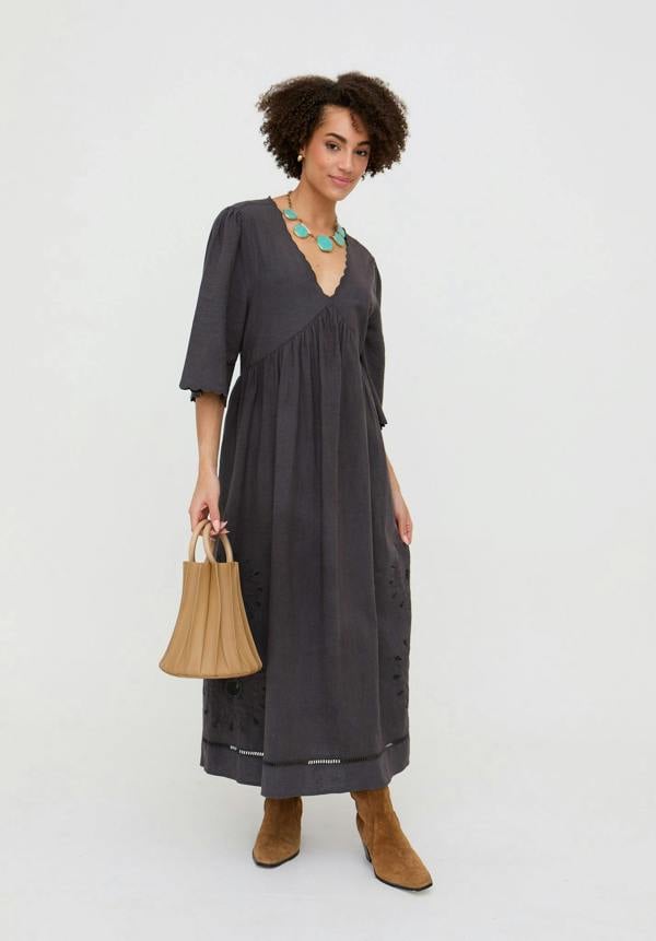 Woman wearing a dark gray dress holding a brown bag on a white background