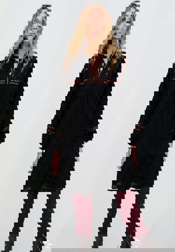 Woman wearing a black dress with red embroidery on a white background