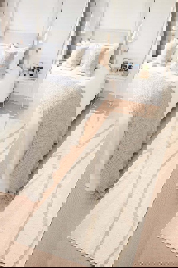 Ava Pave Wave Illusion Rug in cream tones displayed in a cozy bedroom with a bed and decorative pillows.