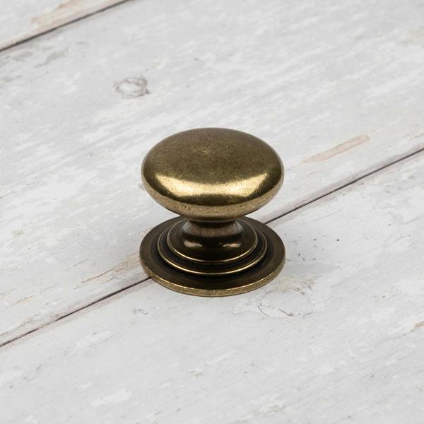 An antique brass round curved classic traditional knob
