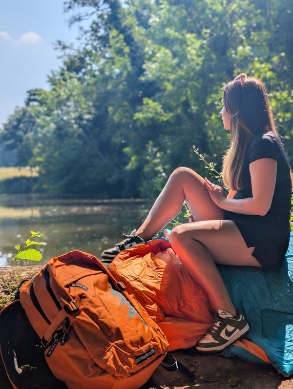 An adult sitting on a tree log using the Blanko for comfort.