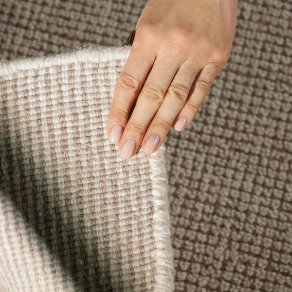 Hand touching textured fabric with a neutral color palette