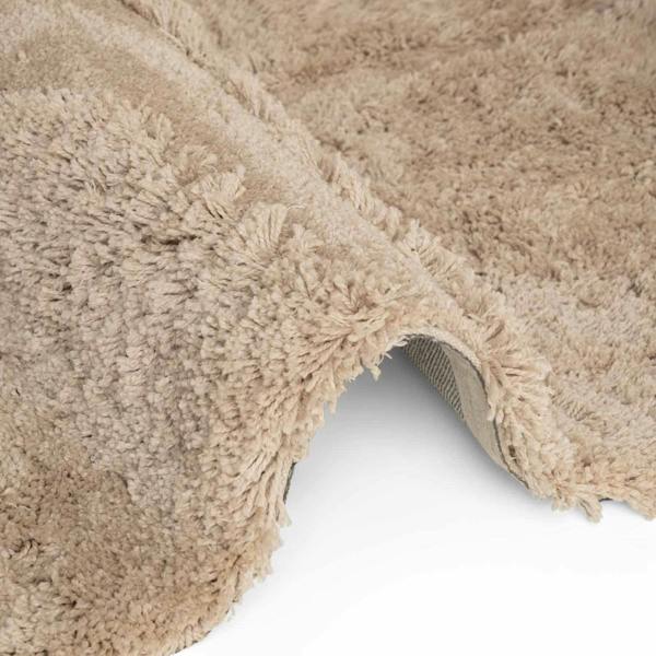 Close-up of a beige shaggy rug corner on a white background