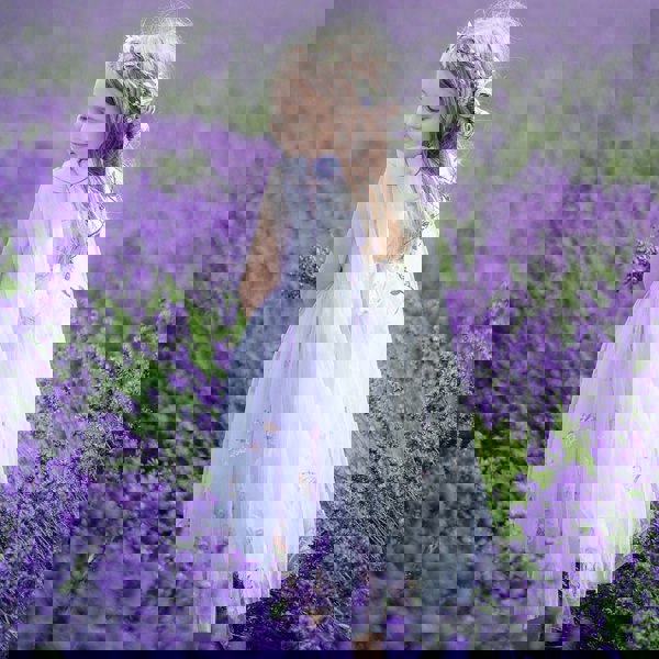 Young girl in a white dress standing in a field of lavender