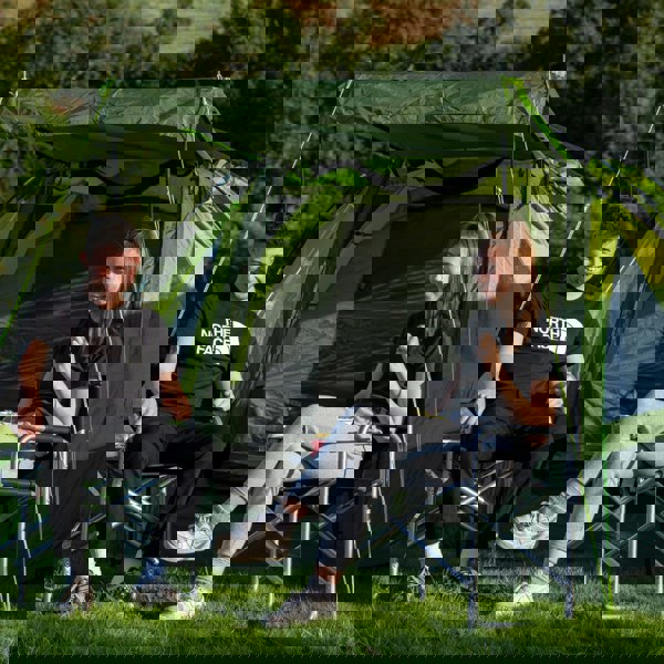 A male and a female sat outside of the Abberley XL 4 Berth Tent by OLPRO at a campsite.