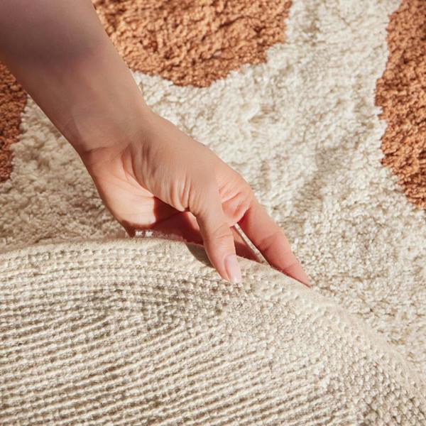 Hand touching a textured beige surface with a circular pattern