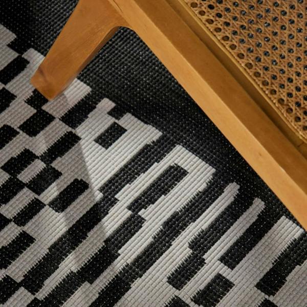 Close-up of a black and white checkered pattern on a textured surface with wooden furniture.