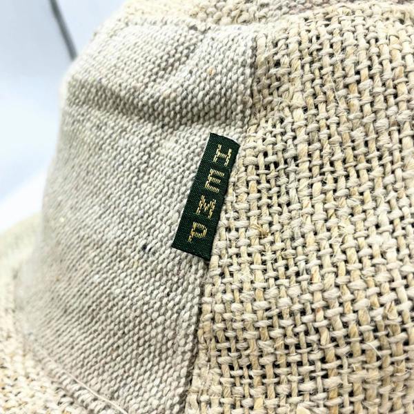 Natural woven hat detail with green brand patch label on crown