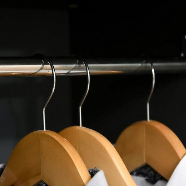 Wooden hangers on a metal hanging rod inside a wardrobe cabinet
