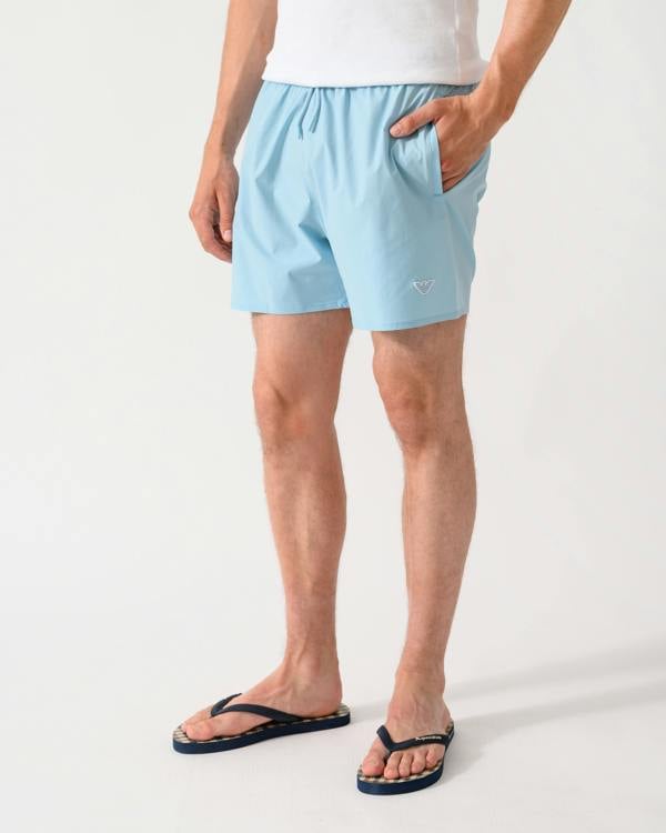 model wearing a pair of Emporio Armani Mens Swim Shorts with Eagle Logo in Sky