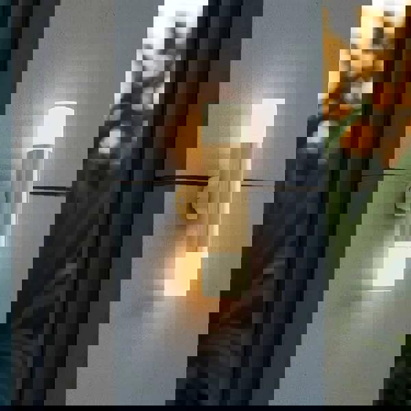 brass up and down exterior light mounted on the concrete wall of a modern house