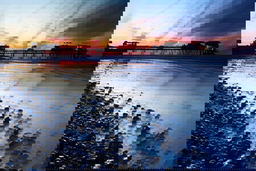 photographic sunset print of cromer pier coastline and rocky beach