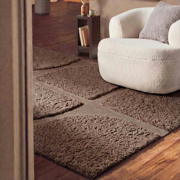 Brown textured rug on a wooden floor with a white armchair in the background.
