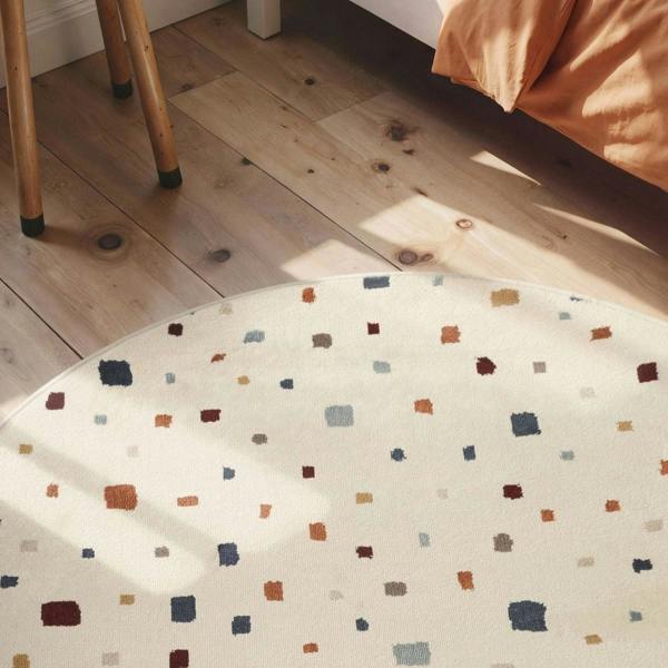 Polka dot fabric on a wooden floor with a chair and bed in the background
