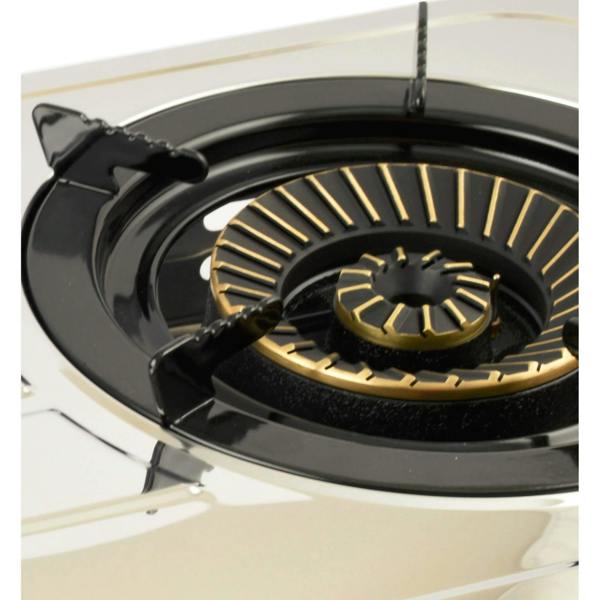 Close-up of a gas stove brass burner with enamel pan support