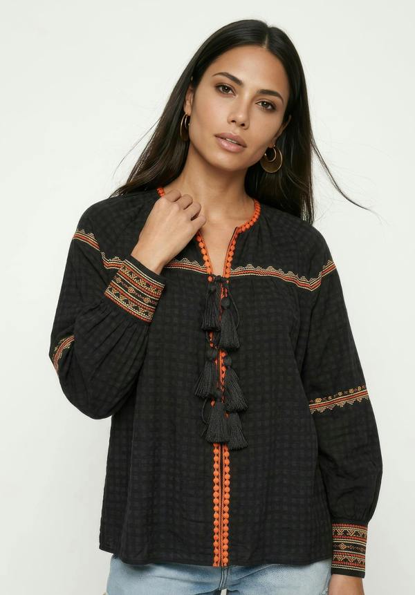 Woman wearing a black blouse with orange patterns on a white background