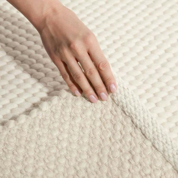 Hand touching a textured beige fabric surface