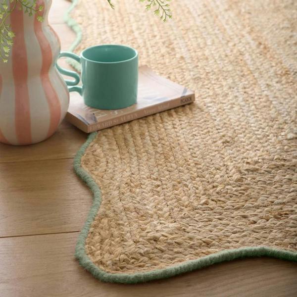 Beige rug on a wooden floor with a cup and remote control on top