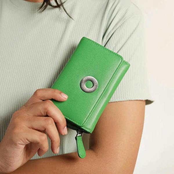 Green wallet with a metallic ring detail held by a person against a neutral background