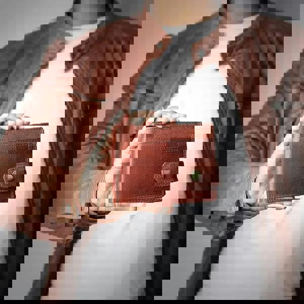 Person holding a brown leather wallet with a blurred background