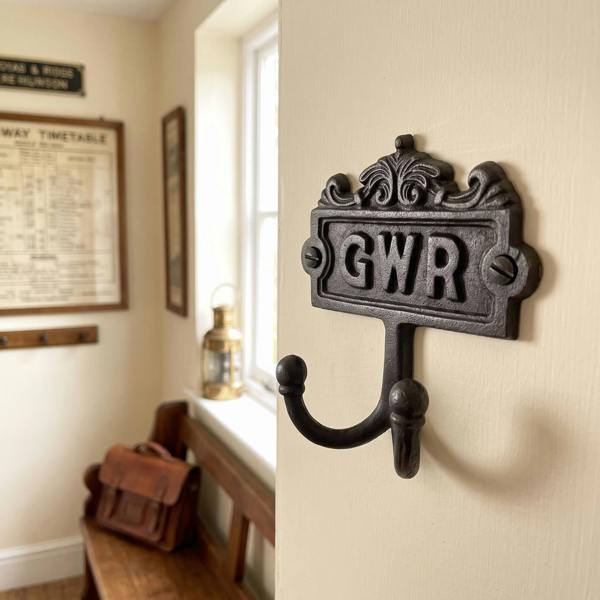 Close-up of vintage-style GWR twin coat hook made of cast iron on a painted wall, highlighting textured dark finish and screw details.