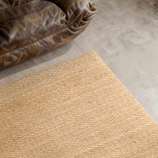 Beige rug on a tiled floor next to a brown leather chair.