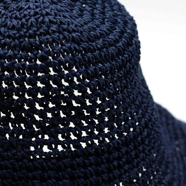 Close-up of navy blue woven straw texture on floppy sun hat brim