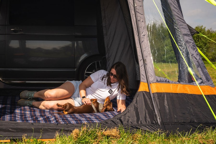 A woman lounges inside the Loopo Breeze® v2 Inflatable Campervan Awning by OLPRO imageset:Charcoal