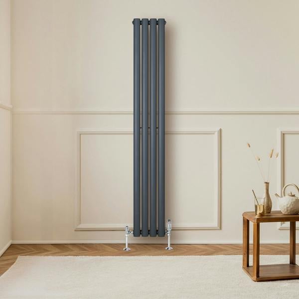 Oval single column radiator in anthracite grey, featuring a sleek design with four vertical tubes, mounted on a light wall above a soft rug