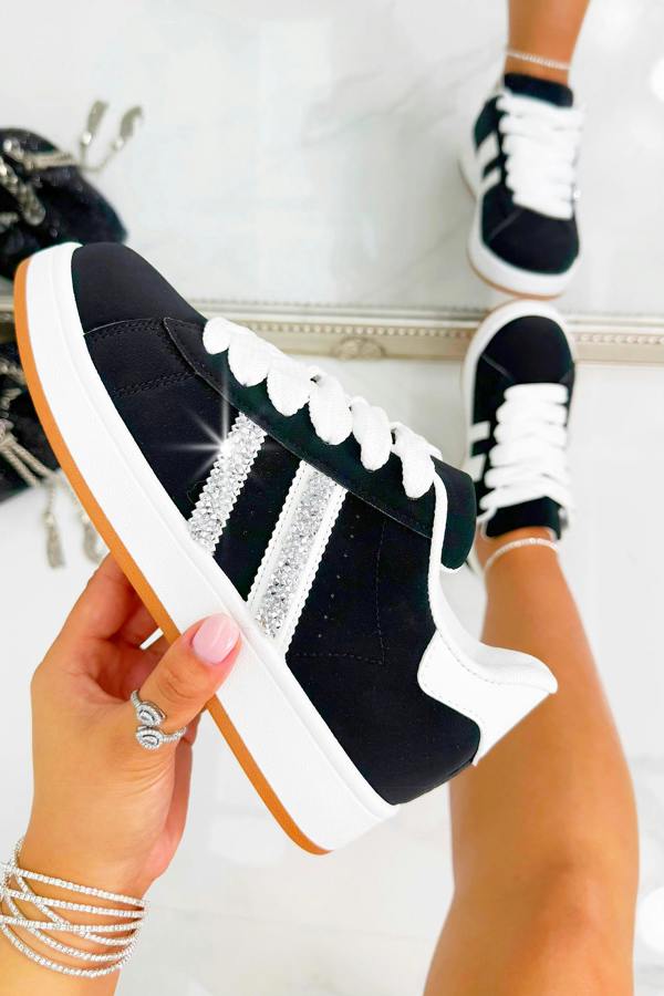 Black and white sneaker with decorative elements held by a hand against a neutral background