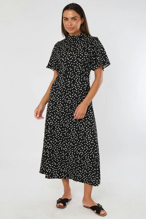 Woman wearing a black dress with white polka dots on a white background