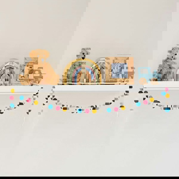 A Handmade Multicoloured Felt Ball Garland adorned with a cute teddy bear and pom poms.
