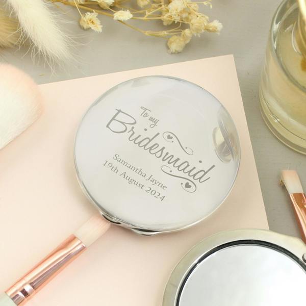Engraved nickel-plated compact mirror reading "To my Bridesmaid" next to its matching black fabric storage pouch on a clean white background.