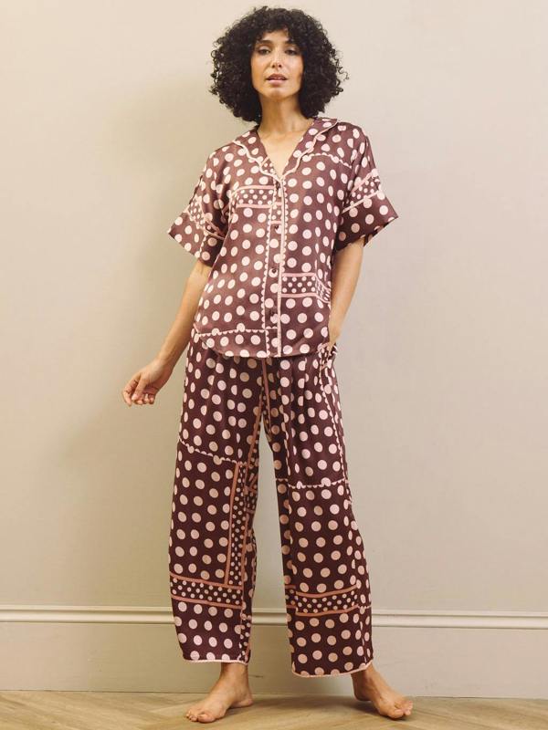 Woman wearing a polka dot pyjama set against a plain background