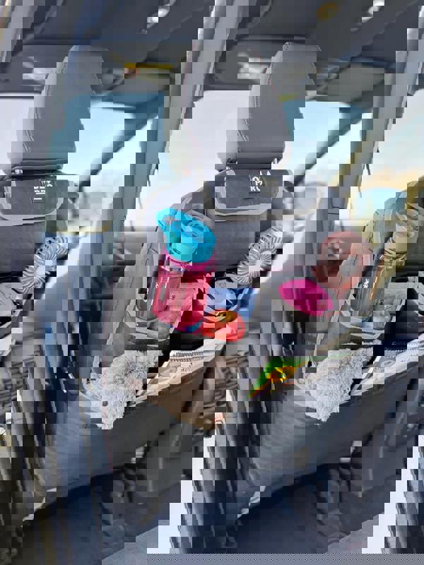 The Rear Single Seat Storage Organiser in Grey by OLPRO being fitted onto the rear of the passenger seat of VW vehicle with some beauty products.