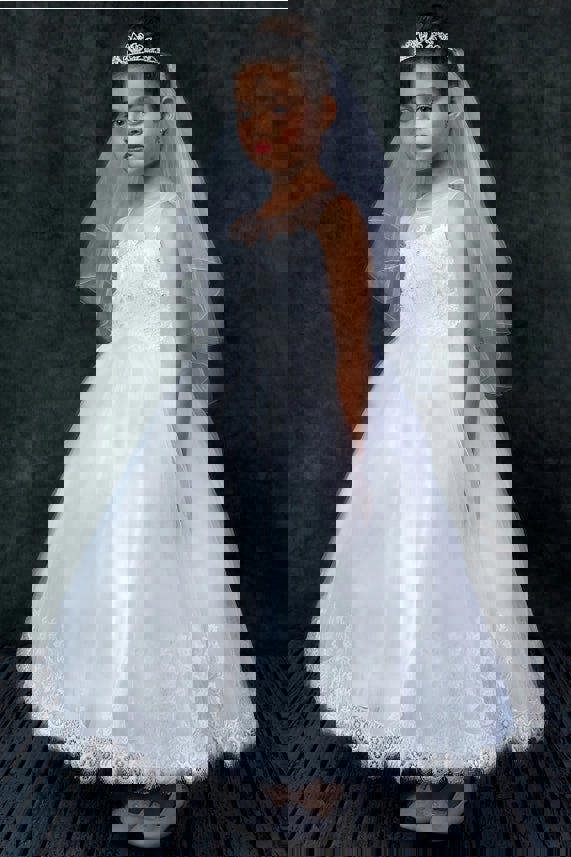 Young girl in a white lace dress with a veil against a dark background