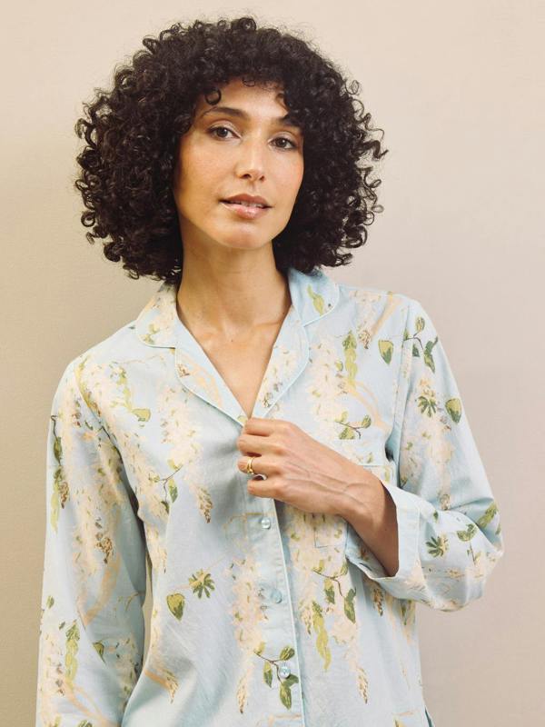 Woman wearing a light blue floral patterned pyjama shirt against a beige background