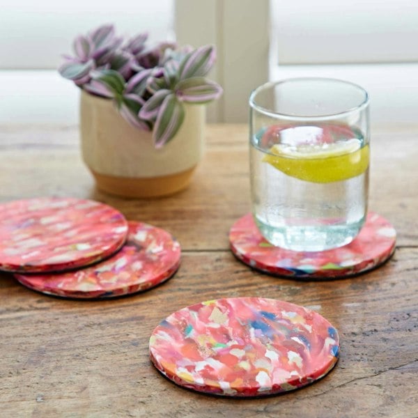 A set of recycled plastic coasters with a glass of water next to them.