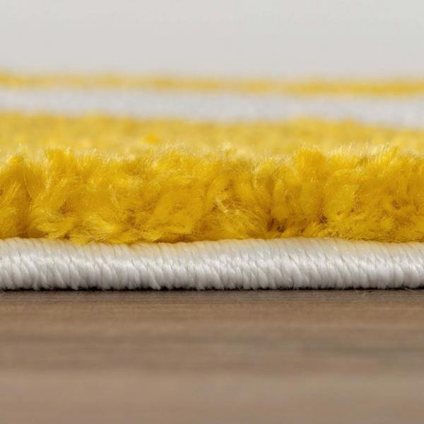 Close-up of yellow and white carpet fibers on a wooden floor.