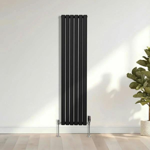 Sleek black oval column radiator with vertical bars, mounted on the wall, complemented by chrome valves and a modern interior setting