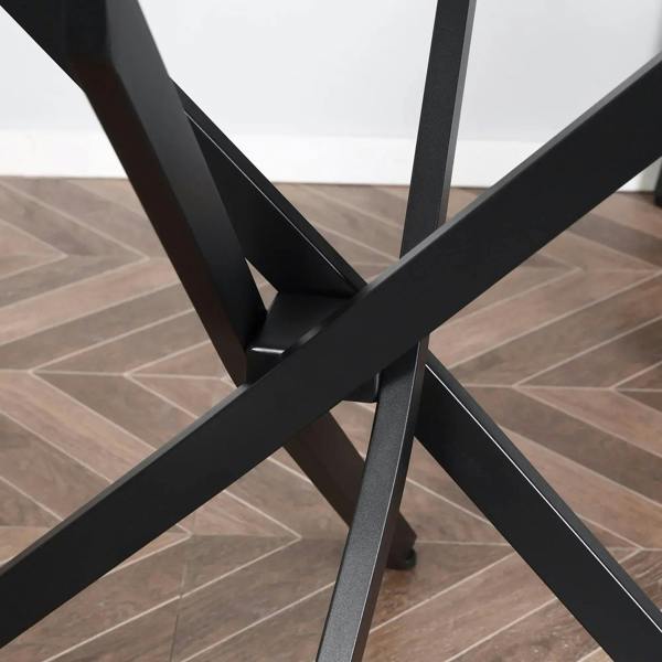 Close-up of black crossed metal legs under a round clear glass table top