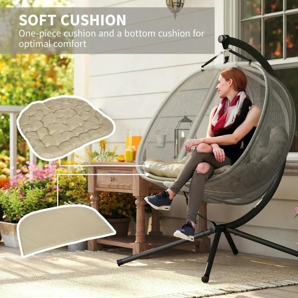 Grey hanging egg chair with beige cushion set on black stand, swing hammock style.