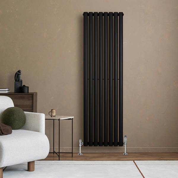 Sleek black oval single column radiator with vertical bars, positioned against a warm-toned wall, complemented by stylish valves